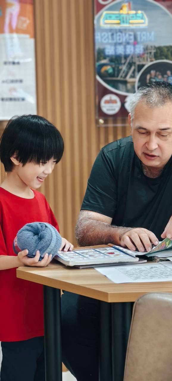 Good Good English 老師與學生一同翻閱書本，開心大笑互動